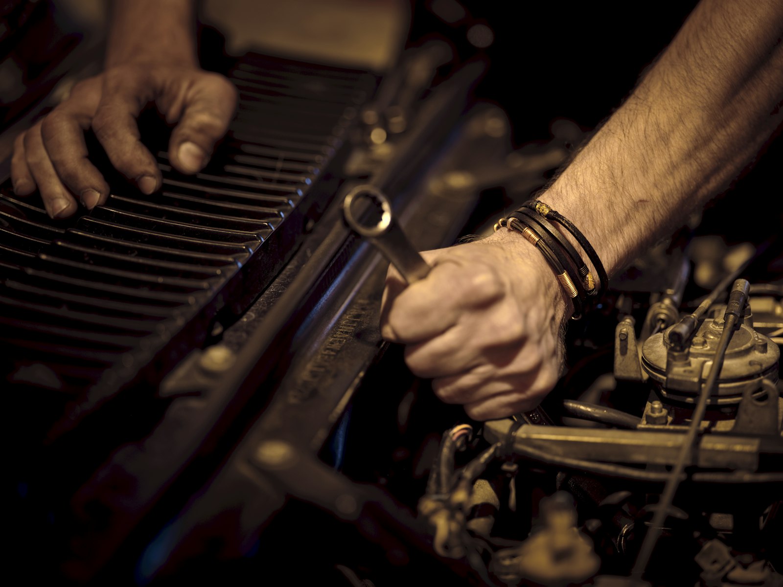 A mechanic's hands working on an engine with a spanner